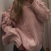 Person wearing a pink knitted sweater taking a mirror selfie.