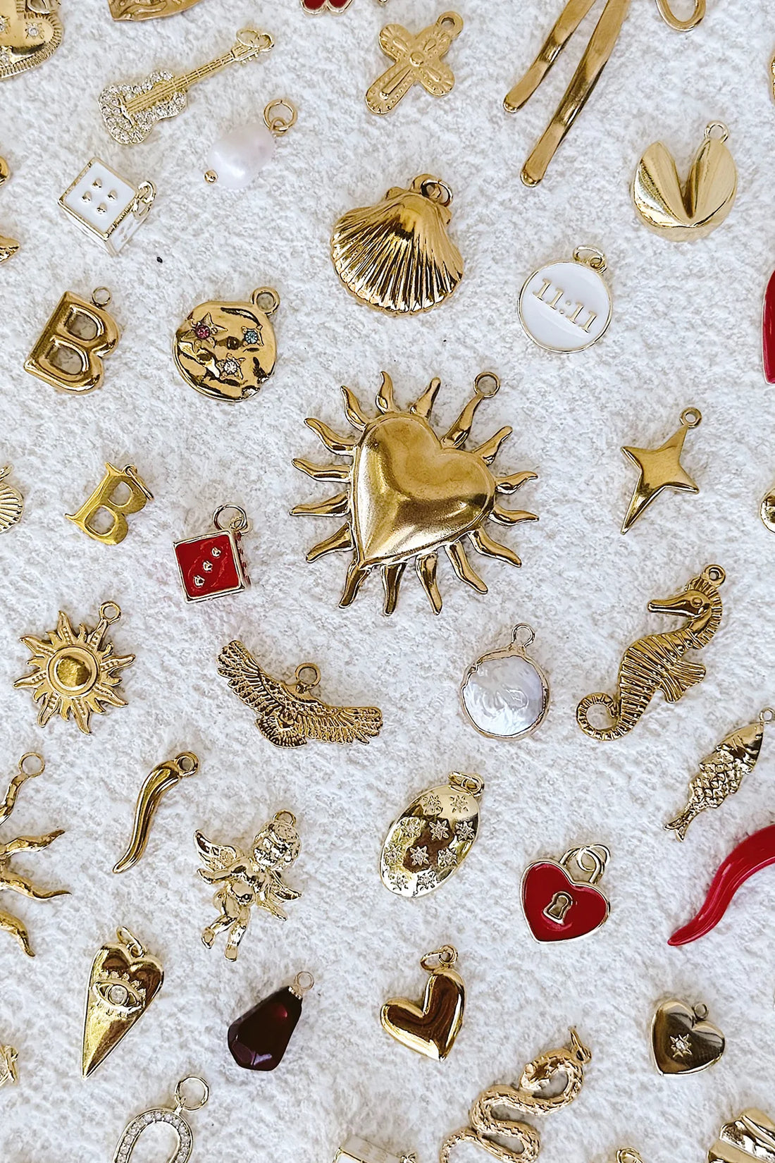 Collection of various gold jewellery charms on a textured white background.