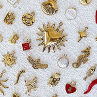 Collection of various gold jewellery charms on a textured white background.