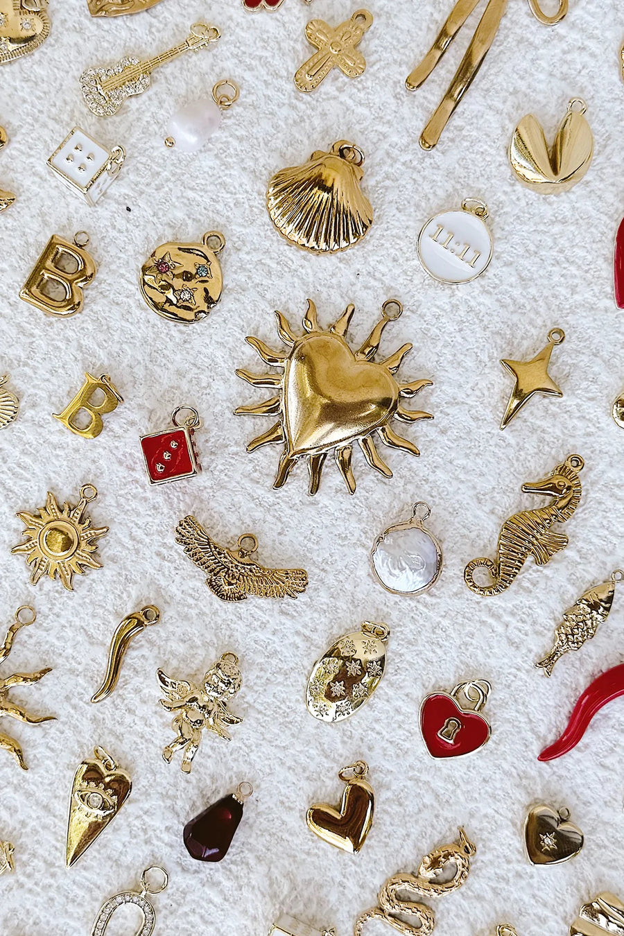 Collection of various gold jewellery charms on a textured white background.